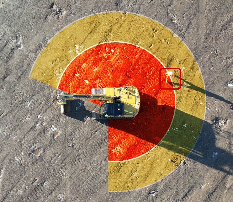 Overhead view of an excavator working inside a marked exclusion zone.
